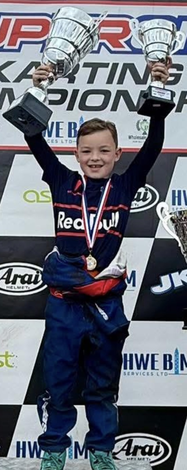Logan holding two trophies on the podium
